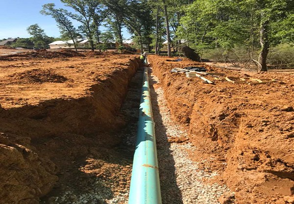 Large pipe being installed in a trench for utility services in a construction project